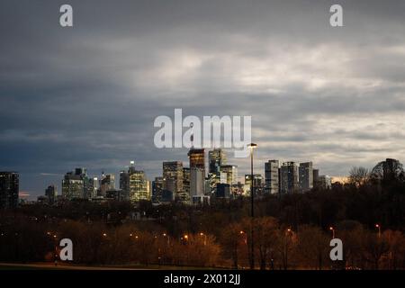 Toronto, Canada. 8 aprile 2024. Vista dello skyline di Toronto dal parco Riverdale a metà giornata, mentre il cielo si oscura durante l'eclissi solare parziale. L'8 aprile 2024, Toronto assisterà ad un'eclissi solare parziale, con una copertura solare del 85% circa. Gli Skywatcher in città osserveranno la luna che passa tra la Terra e il sole, creando un notevole oscuramento della luce solare durante l'evento. Credito: SOPA Images Limited/Alamy Live News Foto Stock