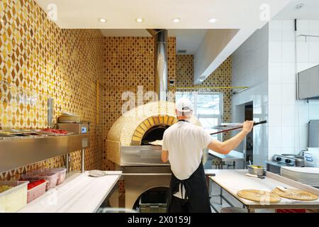 Lo chef prepara la pizza in un tradizionale forno a legna presso un ristorante italiano Foto Stock