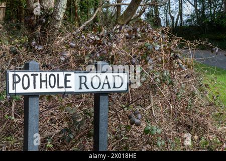 Pothole Road, cartello stradale con il nome effettivo della strada sostituito dalla parola Pothole probabilmente da un autista locale frustrato dal fatto che le buche non sono state riparate, Regno Unito Foto Stock