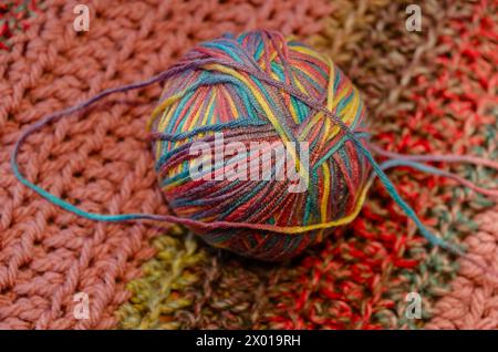 Palla di lana multicolore su una coperta all'uncinetto a mano Foto Stock