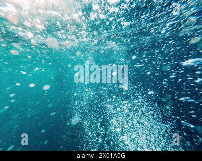 Bolle d'aria subacquea in acqua blu pulita dell'oceano come sfondo naturale, vista dall'angolo basso Foto Stock