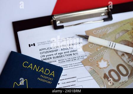 Domanda di cittadinanza canadese per adulti sul tavolo con penna, passaporto e banconote da un dollaro da vicino Foto Stock
