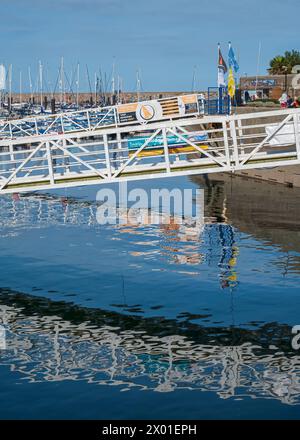 Una passerella per i getti galleggianti nel porto esterno, Brixham, Devon, Inghilterra, Regno Unito, riflettono nelle acque tranquille Foto Stock