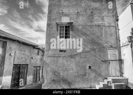 Immagine in bianco e nero di vecchi edifici in una vecchia area urbana di una città mediorientale con porte di legno che si affacciano su negozi chiusi. Foto Stock