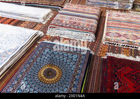 Assortimento di tappeti di seta orientali in vendita con motivi geometrici colorati rappresentati nello storico bazar di Bukhara Foto Stock