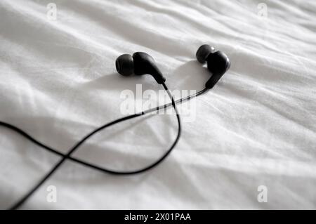 auricolari su lenzuolo bianco pieghe Foto Stock