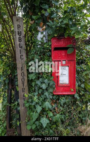 NETHER STOWEY, Regno Unito - 23 AGOSTO 2017: Una cassetta postale circondata da edera accanto a un cartello per un sentiero pubblico. Foto Stock