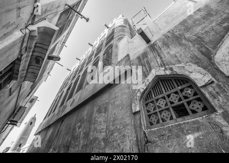 Un'immagine monocromatica filtrata di una finestra ad arco con un reticolo di legno nel muro di un edificio abbandonato e abbandonato in Medio Oriente in una al Foto Stock