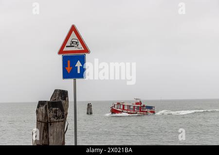 Segnaletica stradale Priority nel traffico in avvicinamento e attenzione lungo la costa della laguna di Venezia. Traghetto passeggeri nel backgrou Foto Stock