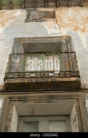 Un primo piano di un antico balcone con ringhiere ornate su un vecchio edificio urbano con pareti in angoscia Foto Stock