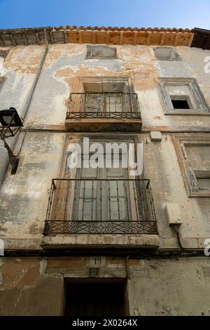 Un primo piano di un antico balcone con ringhiere ornate su un vecchio edificio urbano con pareti in angoscia Foto Stock