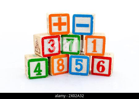 Blocchi di legno con numeri e segno più e meno isolati su sfondo bianco. Concetto di apprendimento matematico. Foto Stock