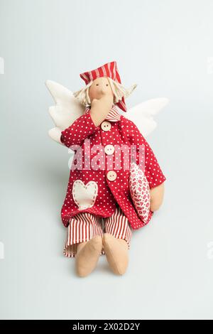 Bambola di lino per bambini addormentati in pigiama di cotone rosso isolato su sfondo bianco, giocattolo o decorazione interna Foto Stock