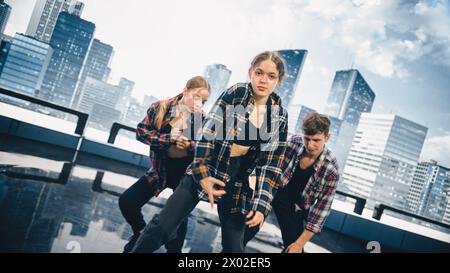 Gruppo eterogeneo di tre giovani ballerini professionisti che eseguono una routine di danza hip hop da vicino davanti a un grande schermo LED con un moderno skyline urbano con grattacieli Office in ambiente Studio. Foto Stock