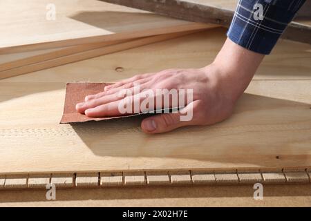 Uomo che lucida tavole di legno con carta vetrata, primo piano Foto Stock