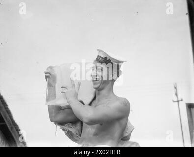 MOMENTI TROPICALI. 7 E 8 AGOSTO 1945, HMS RAJALYIA, ROYAL NAVAL AIR STATION PUTTALAM, CEYLON. ATTIVITÀ E PERSONALITÀ ALLA ROYAL NAVAL AIR STATION. - Able Seaman Leonard King, di Nottingham, fa ghiaccio per la HMS RAJALYIA al servizio della flotta britannica delle Indie Orientali. Ogni giorno entra in un grande frigorifero e raccoglie 20 blocchi di materiale, ciascuno del peso di 70 kg Foto Stock