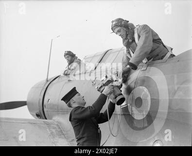 GLI OCCHI FOTOGRAFICI DELLA FLOTTA. 4 MARZO 1943, ROYAL NAVAL AIR STATION, STRETTON, LANCS, SI SENTE POCO DEI FOTOGRAFI CHE VOLANO CON AEREI NAVALI PER OTTENERE I REGISTRI DELLE ATTIVITÀ NEMICHE E DEI RISULTATI DEI NOSTRI ATTACCHI. - Un rating che consegna la telecamera al fotografo dell'aereo Foto Stock