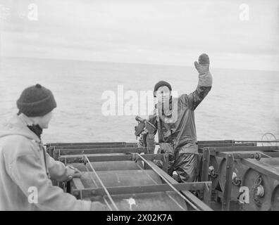 CON UN PESCHERECCIO A STRASCICO SULLA PATTUGLIA DEL NORD. MAGGIO 1942, A BORDO DEL PESCHERECCIO DA TRAINO HM NORTHERN SKY, CHE OPERA SULLA PATTUGLIA SETTENTRIONALE DA SCAPA. MEMBRI DELL'EQUIPAGGIO DELLA HMS NORTHERN SKY IN UNO DEI LAVORI PIÙ DIFFICILI IN MARE, LA PATTUGLIA SETTENTRIONALE. - Il rating a poppa che segnala al ponte che è pronto a far cadere le cariche di profondità Foto Stock