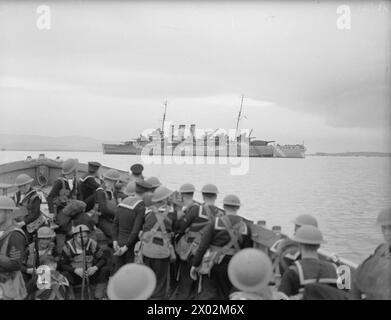 CON I ROYAL MARINES A TERRA E A GALLA. 1940, A BORDO DELLA HMS RODNEY E A TERRA. I VARI COMPITI SVOLTI DAI ROYAL MARINES. - Una parte di sbarco che ritorna alla propria nave dopo l'esercitazione. La HMS NORFOLK è sullo sfondo della Royal Navy, NORFOLK (HMS) Foto Stock