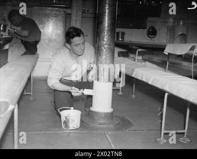 CON I ROYAL MARINES A TERRA E A GALLA. 1940, A BORDO DELLA HMS RODNEY E A TERRA. I VARI COMPITI SVOLTI DAI ROYAL MARINES. - Marine Palmer è una spazzatrice di coperta e lavora anche nella torretta da 16' Foto Stock