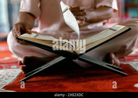 Uomo musulmano seduto a leggere il Corano il libro sacro dell'Islam, Moschea Mubarak, Chau Doc, Vietnam, Indocina, sud-est asiatico, Asia Foto Stock