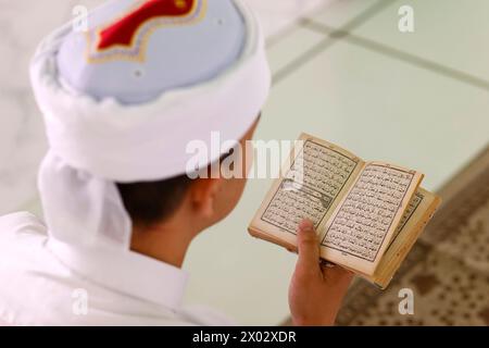 Uomo musulmano che legge un Sacro Corano arabo, Moschea Jamiul Azhar, Vietnam, Indocina, Sud-est asiatico, Asia Foto Stock