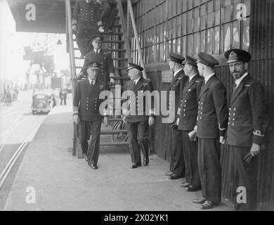 NORE C-IN-C VISITA IL SOTTOCOMANDO DI HARWICH. 20 LUGLIO 1943. AMMIRAGLIO SIR JOHN C TOVEY, KCB, KBE, DSO, NUOVO C-IN-C NORE, HO FATTO UNA VISITA NON CERIMONIALE AL SOTTOCOMANDO DI HARWICH. FU ACCOMPAGNATO NEL SUO TOUR DAL CONTRAMMIRAGLIO H H ROGERS, MVO, OBE. - Ammiraglio Sir John Tovey con il contrammiraglio H H Rogers che lascia uno dei negozi navali Foto Stock