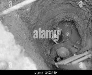 SMALTIMENTO DELLA BOMBA TEDESCA DA 1000 KG. 11 E 12 GENNAIO 1943, DEVONPORT. - I membri della squadra di smaltimento delle bombe che scendono nel buco per iniziare a lavorare alla rimozione della bomba, che si trova a 18 piedi sotto terra Foto Stock