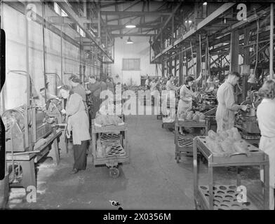 SOTTO FUOCO - COME RICOMPENSA: PRODUZIONE E TEST DI BOMBE MORTAI PRESSO LA J & F POOL'S NO 1 WORKS, HAYLE, CORNOVAGLIA, INGHILTERRA, 1943 - i lavoratori della piccola fabbrica di J & F Pool Ltd gestiscono torni per alesare e affrontare le estremità del naso delle bombe mortai. Si tratta della prima operazione eseguita dopo la consegna dei pezzi fusi grezzi dalla fonderia. Sullo sfondo è visibile una pila di pezzi fusi grezzi in attesa di lavoro Foto Stock