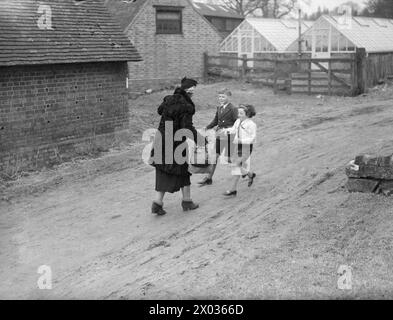 THE CARTERS IN WARTIME: EVERYDAY LIFE FOR A BRITISH FAMILY ON THE HOME FRONT, ENGLAND, C 1940 - Michael e Angela Carter corrono a salutare la madre al suo arrivo nella loro casa evacuata a Hayward's Heath, nel Sussex. La signora Carter ha viaggiato sul treno da Londra Victoria per visitarli Foto Stock