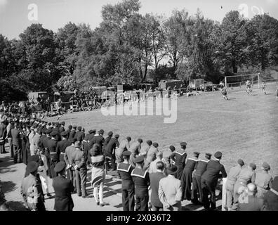 PARTITA DI FOOTBALL DELLA MARINA SUL CAMPO DI CALCIO GIOVANILE DI HITLER. MAGGIO 1945, KIEL. LA PARTITA DI CALCIO GIOCATA NELL'EX CAMPO SPORTIVO DEL MOVIMENTO GIOVANILE HITLER TRA IL NAVAL PARTY 1734 (BASATO SULLA NAVE AMMIRAGLIA) E LA 30A UNITÀ D'ASSALTO DELLA ROYAL MARINE E DELLA ROYAL NAVY COMMANDOS, CHE HA VINTO 4-3. I CIVILI TEDESCHI, GIOVANI E VECCHI, SI SONO ACCORSI PER VEDERE IL GIOCO E PER ASCOLTARE LA BANDA DI PIPA DEI CAMERONIANS, MA NON C'È STATA ALCUNA FRATERNIZZAZIONE. - Scena generale durante un attacco all'obiettivo delle unità d'assalto Foto Stock