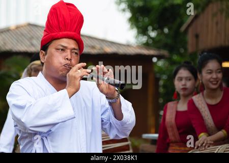 L'uomo asiatico suona il flauto. Artisti vietnamiti che eseguono musica e balli tradizionali. Musicisti che suonano un flauto e un tamburo, in abiti tradizionali- Foto Stock