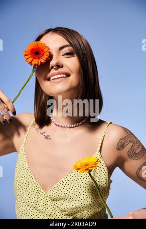 Una giovane donna con i capelli bruna tiene in mano un fiore vibrante. Foto Stock