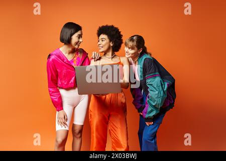 Tre donne - caucasiche, asiatiche, afroamericane - si uniscono su uno sfondo arancione dello studio, che irradia bellezza e diversità. Foto Stock