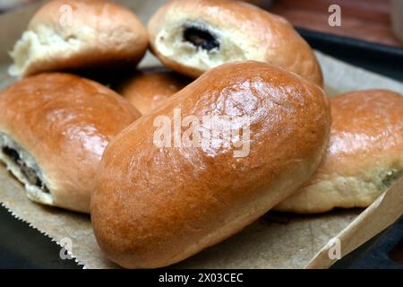 Ci sono torte con semi di papavero ripieni all'interno in un cumulo su una teglia da forno, primo piano. Foto Stock