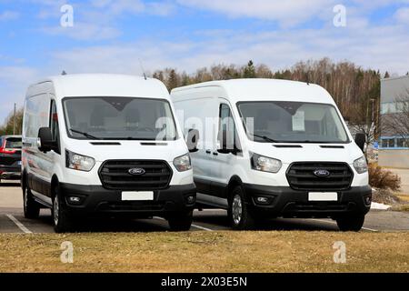 Due nuovi furgoni bianchi Ford Transit EcoBlue Hybrid parcheggiati all'esterno presso una concessionaria. Salo, Finlandia. 31 marzo 2024. Foto Stock