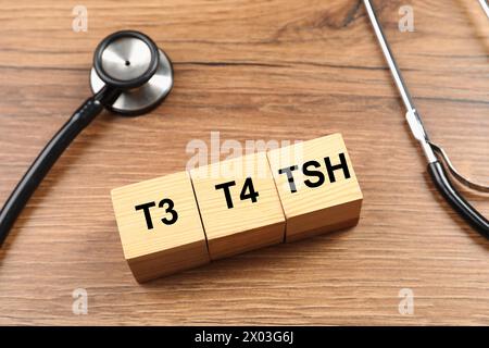 Endocrinologia. Stetoscopio e cubetti con ormoni tiroidei su un tavolo di legno Foto Stock