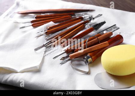 Set di diversi utensili per la lavorazione dell'argilla su tavolo in legno, primo piano Foto Stock