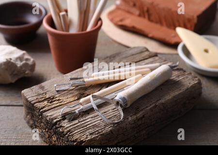 Set di diversi utensili per la lavorazione dell'argilla su tavolo in legno, primo piano Foto Stock