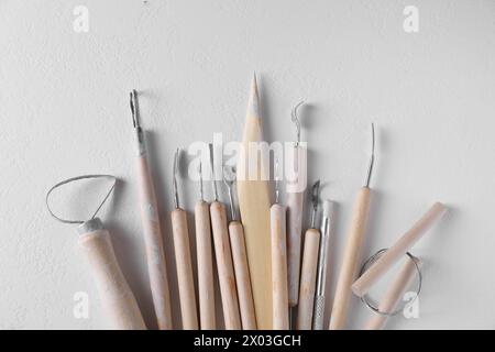 Set di diversi strumenti per la creazione dell'argilla su tavolo bianco, vista dall'alto Foto Stock