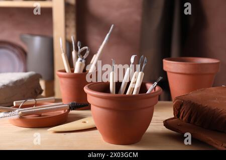 Set di diversi utensili per la lavorazione dell'argilla su un tavolo in legno in officina Foto Stock