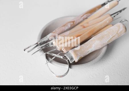 Set di diversi strumenti per la lavorazione dell'argilla su tavolo bianco Foto Stock