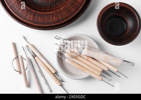 Set di diversi strumenti per la lavorazione dell'argilla su tavolo bianco Foto Stock