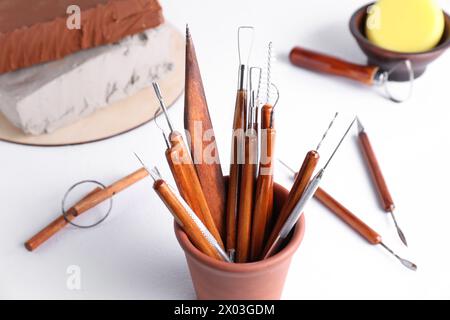 Argilla e set di strumenti per la lavorazione su tavolo bianco, primo piano Foto Stock