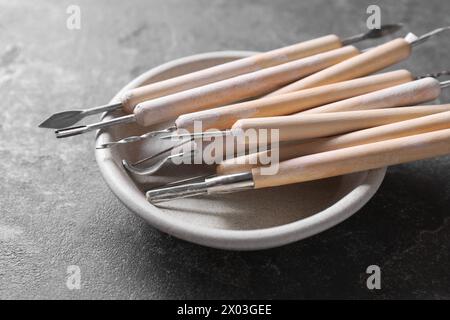 Set di diversi strumenti per la lavorazione dell'argilla su tavolo grigio, primo piano Foto Stock