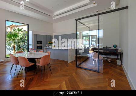 HAMALA, BAHREIN - 2 MARZO 2019: Elegante cucina modernista open space e sala da pranzo di una villa di lusso con un ufficio con pareti in vetro su un lato e un Foto Stock