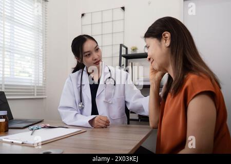 Un medico donna chiede informazioni sul sintomo di una paziente anziana che soffre di stress o mal di testa. e tenere la spalla per incoraggiare Foto Stock