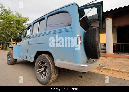 156 Vecchia auto in alluminio azzurro -1955 Jeep Willys Classic, stazionata su una strada nel centro città all'inizio del tramonto. Viñales-Cuba. Foto Stock