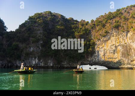 Turisti in barca tra rocce calcaree in una grotta di archi nella baia di LAN ha, vicino alla baia di ha Long, in Vietnam Foto Stock