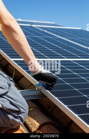 Primo piano di un tecnico MAN con guanti da lavoro che installano pannelli solari fotovoltaici autonomi Foto Stock